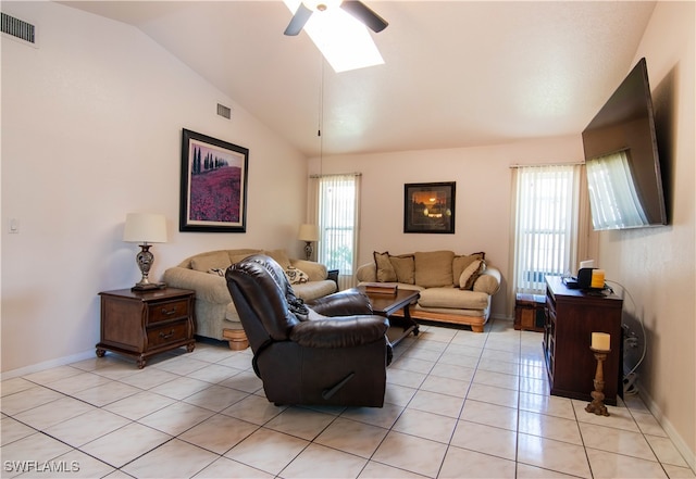 living room featuring ceiling fan, vaulted ceiling with skylight, and light tile patterned floors