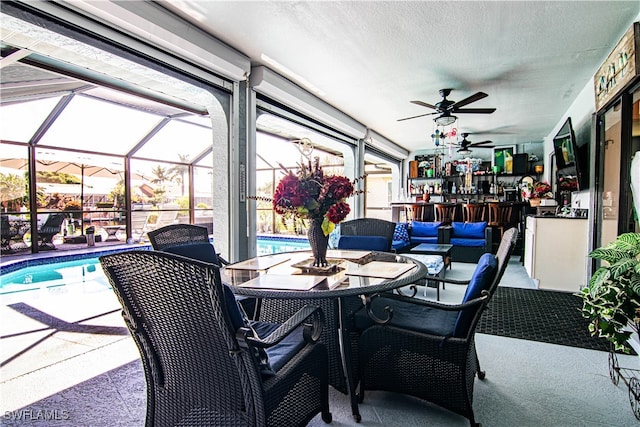 view of patio with ceiling fan and glass enclosure