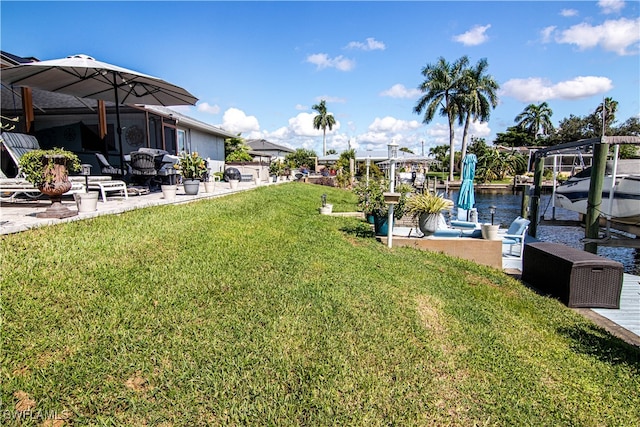 view of yard featuring a water view, a boat dock, and a patio area