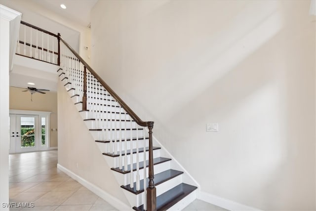 staircase featuring french doors, ceiling fan, tile patterned floors, and a towering ceiling