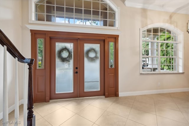 foyer entrance featuring french doors, light tile patterned floors, and a high ceiling