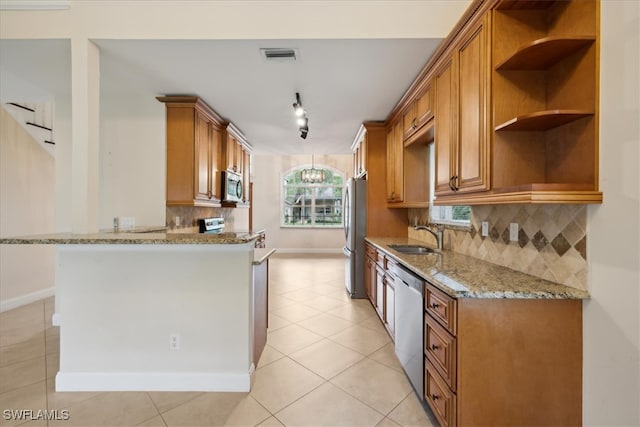 kitchen featuring sink, light stone countertops, a chandelier, appliances with stainless steel finishes, and tasteful backsplash