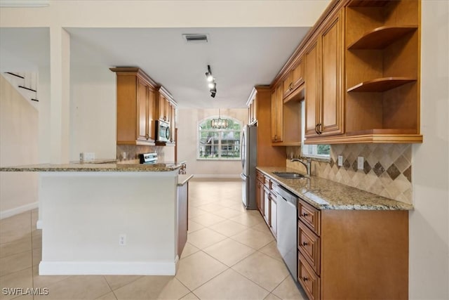 15621 Red Fox Run, Fort Myers, FL 33912 - kitchen featuring appliances with stainless steel finishes, brown cabinetry, light stone countertops, decorative backsplash, and light tile patterned flooring