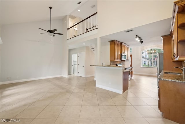 kitchen featuring sink, ceiling fan with notable chandelier, stainless steel appliances, high vaulted ceiling, and light tile patterned floors