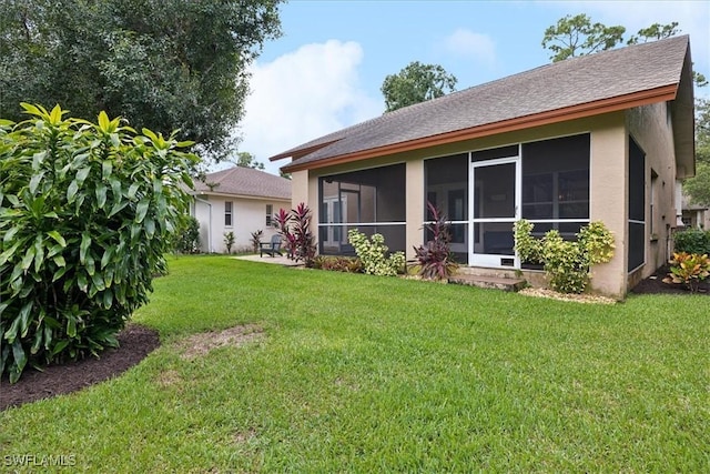 15621 Red Fox Run, Fort Myers, FL 33912 - rear view of house with a sunroom, stucco siding, a yard, and roof with shingles