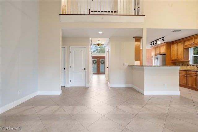 kitchen with stainless steel fridge, light stone countertops, light tile patterned floors, and plenty of natural light