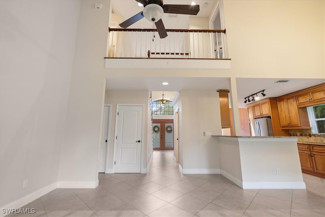 kitchen with stainless steel fridge, light stone counters, and a high ceiling