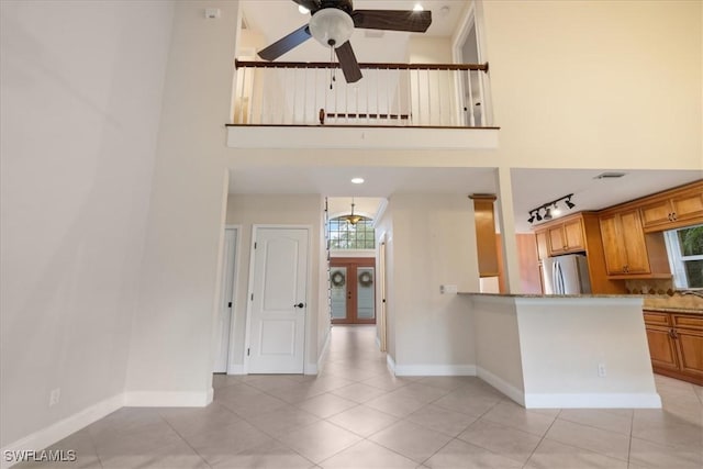 15621 Red Fox Run, Fort Myers, FL 33912 - kitchen with freestanding refrigerator, a ceiling fan, light tile patterned flooring, brown cabinets, and light stone countertops