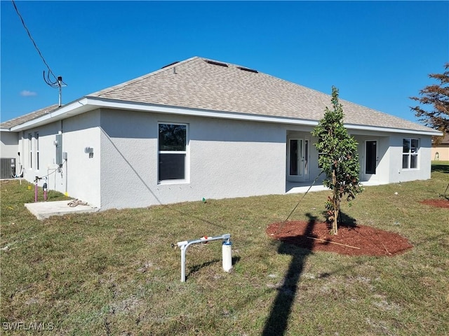 back of property featuring central AC and a lawn