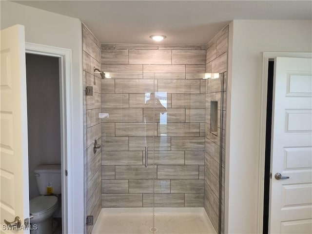 bathroom with a shower with shower door and toilet