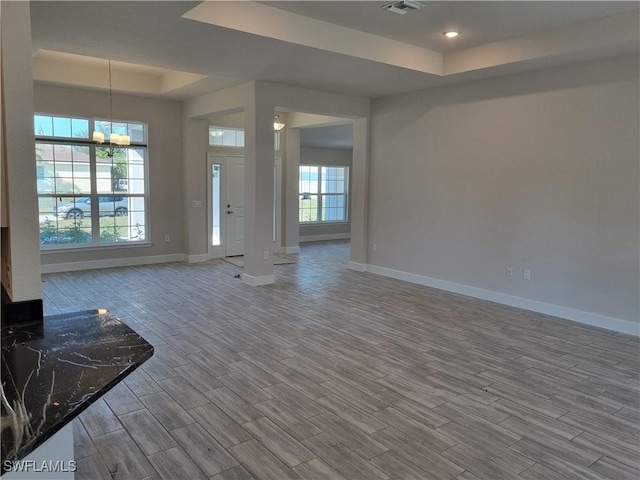 unfurnished living room featuring a notable chandelier and a tray ceiling