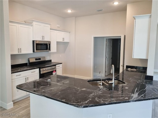 kitchen featuring white cabinetry, stainless steel appliances, sink, and light wood-type flooring