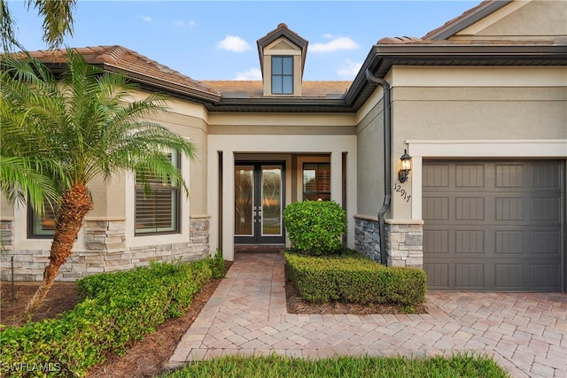 property entrance featuring a garage, stone siding, and stucco siding