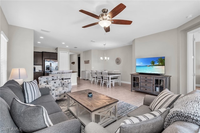 living room with ceiling fan with notable chandelier and light tile patterned floors