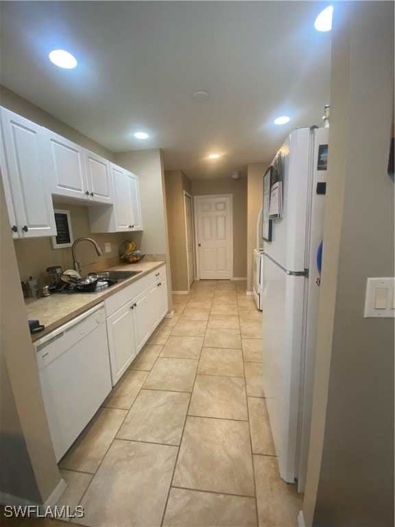 kitchen with white appliances, white cabinetry, sink, and light tile patterned floors