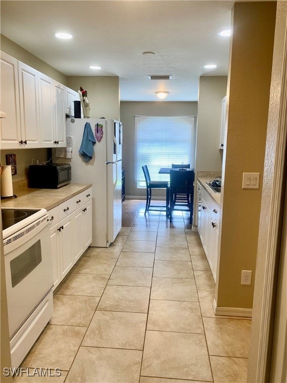 kitchen with white appliances, white cabinetry, and light tile patterned floors