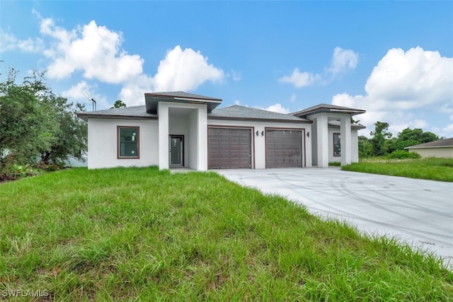 prairie-style house featuring a garage and a front lawn