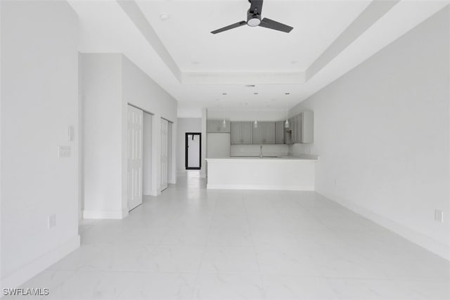 unfurnished room featuring ceiling fan, a raised ceiling, and sink