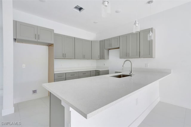 kitchen with pendant lighting, sink, kitchen peninsula, and gray cabinets