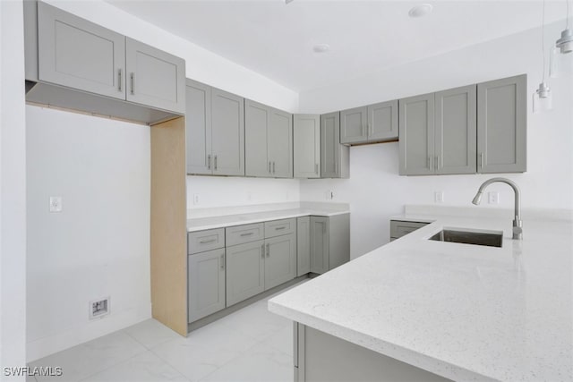 kitchen featuring gray cabinetry, sink, and decorative light fixtures