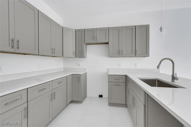 kitchen with sink, gray cabinets, and decorative light fixtures