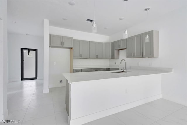 kitchen with gray cabinets, decorative light fixtures, sink, and kitchen peninsula