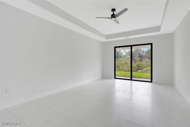 empty room featuring a tray ceiling and ceiling fan