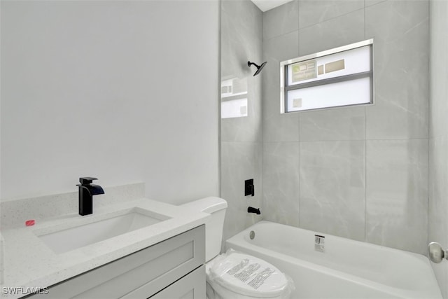 full bathroom featuring tiled shower / bath, vanity, and toilet