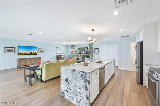 kitchen with appliances with stainless steel finishes, hanging light fixtures, light hardwood / wood-style floors, and white cabinetry