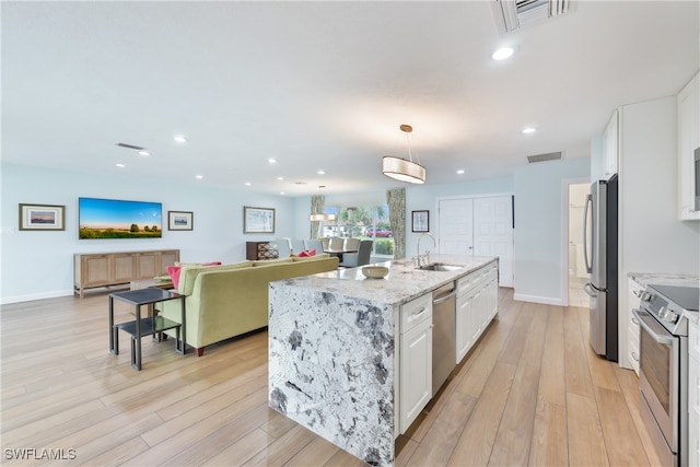 kitchen with white cabinetry, pendant lighting, stainless steel appliances, light hardwood / wood-style flooring, and sink