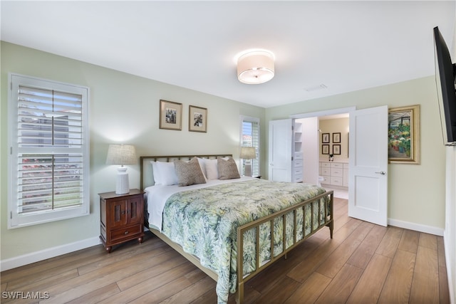 bedroom with connected bathroom and light hardwood / wood-style floors