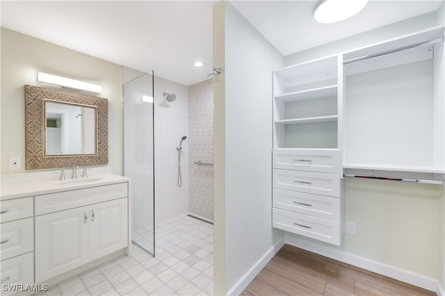 bathroom with a tile shower, vanity, and hardwood / wood-style flooring