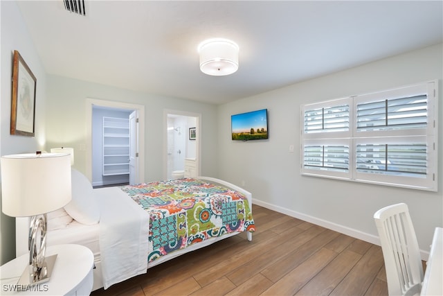 bedroom with connected bathroom and hardwood / wood-style flooring