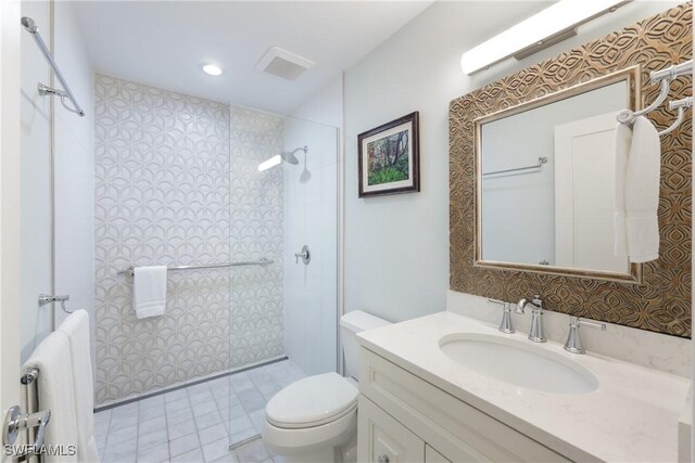 bathroom with a tile shower, vanity, and toilet