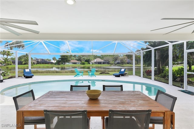 view of pool with ceiling fan, a water view, a lanai, and a patio area