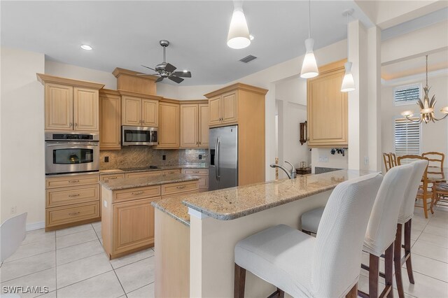 kitchen with light stone counters, kitchen peninsula, decorative light fixtures, stainless steel appliances, and ceiling fan with notable chandelier