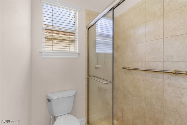 bathroom featuring a shower with door and toilet