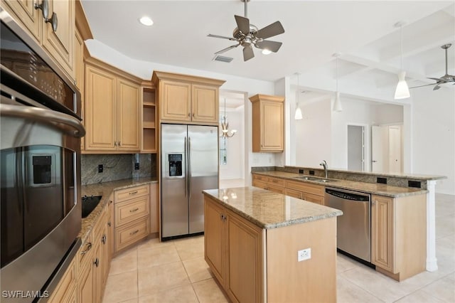 kitchen with stainless steel appliances, a ceiling fan, a sink, a peninsula, and a kitchen island