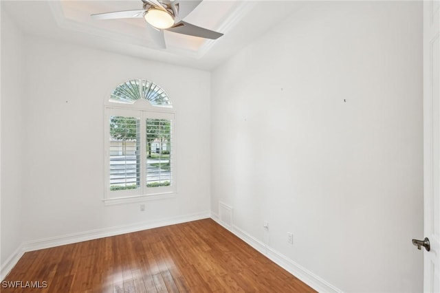 unfurnished room featuring wood-type flooring, a tray ceiling, baseboards, and a ceiling fan