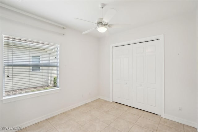 unfurnished bedroom with baseboards, a closet, a ceiling fan, and light tile patterned floors