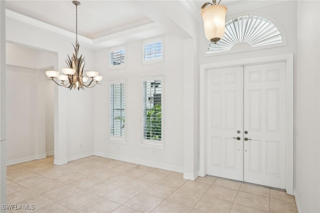 entrance foyer featuring a chandelier, light tile patterned flooring, baseboards, and a towering ceiling