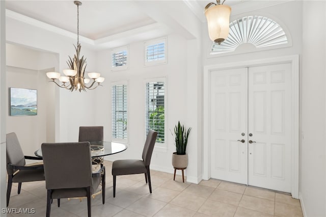 dining space with a chandelier, light tile patterned flooring, baseboards, a tray ceiling, and a high ceiling