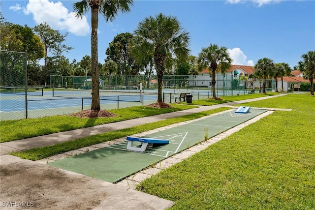 view of property's community with tennis court and a yard