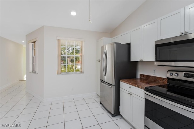 kitchen featuring lofted ceiling, appliances with stainless steel finishes, light tile patterned flooring, and white cabinetry