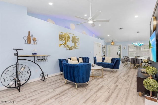 living room featuring ceiling fan with notable chandelier, lofted ceiling, and light wood-type flooring