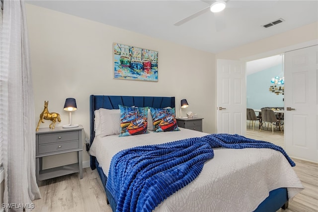 bedroom featuring ceiling fan with notable chandelier, vaulted ceiling, and light hardwood / wood-style floors