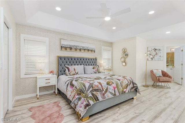 bedroom featuring a raised ceiling, ceiling fan, and light hardwood / wood-style flooring