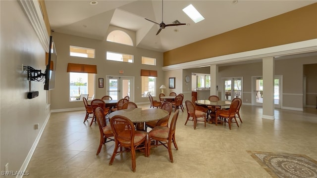 tiled dining area with ceiling fan and high vaulted ceiling