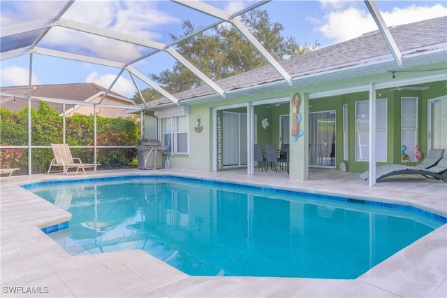 view of swimming pool with glass enclosure, area for grilling, and a patio