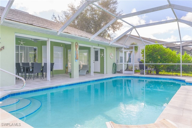 view of swimming pool featuring glass enclosure, ceiling fan, and a patio